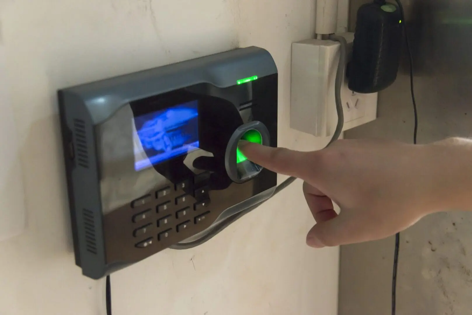 A person scanning his finger in a security lock with buttons on it.